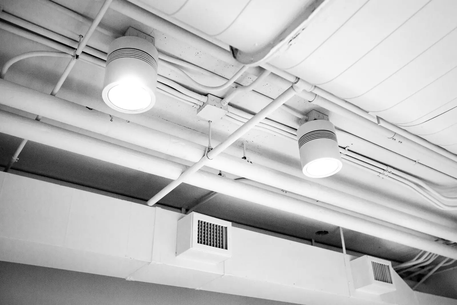 White ceiling with an exposed ventilation duct and a ceiling vent